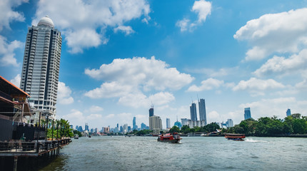 Fototapeta premium Tourist popular boat travel on the Chao Phraya river, Bangkok, Thailand. Bangkok city buildings cityscape. Skyscrapers of western bank of Chao Praya River are seen on the horizon.