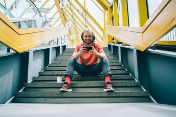 Man sitting on stairway of enclosed pedestrian bridge and smiling