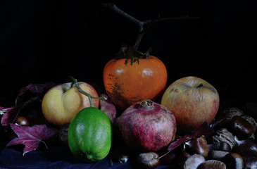 apples, persimmon and a green lemon on black background