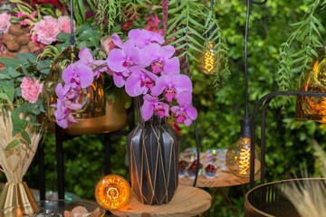 Luxurious wedding party decoration. Decoration with orchid, retro lamp bulb, colorful flowers, golden tray. Copy space Selective focus.