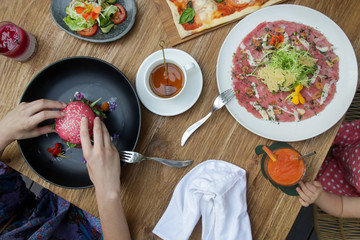 Woman eating vegetarian pink burger, healthy dishes served on the restaurant table