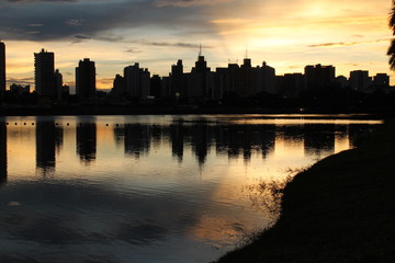 Golden sunset over the São José do Rio Preto reservoir, with silhouettes of palm trees and...