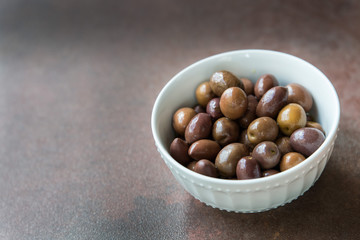 White ceramic bowl full of Mediterranean black and green olives