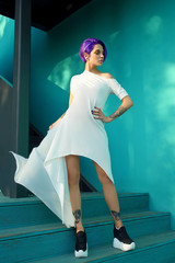 Beautiful girl on background of bright cyan-mint color wall in summer white dress