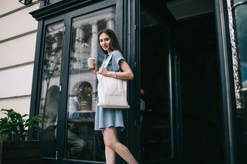 Obraz premium Young woman with takeaway coffee and fabric bag leaving coffee shop