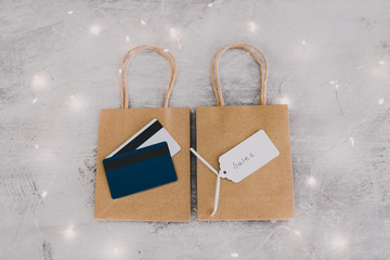 marketing and purchases concept, shopping bags from topdown perspective with payment cards and price tag surrounded by fairy lights bokeh