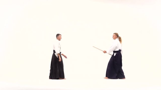 Two athletes performing aikido using bokken. Isolated, white. Slow motion.