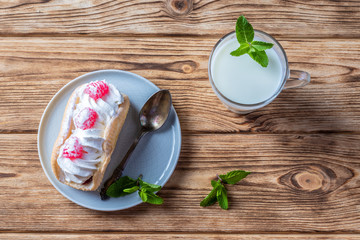 Kefir is decorated with a leaf of mint, a fermented drink. Air cake on a saucer. wood background