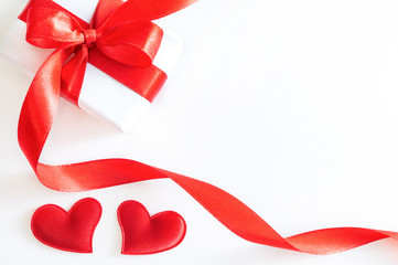 White gift or present box with red ribbon, and decorative hearts on white background. Holiday concept, flat lay, top view.