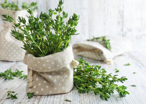 Fresh green thyme in decorative linen bag on an old wooden table.