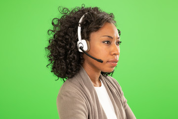 African female operator with headset listening to client on greenscreen