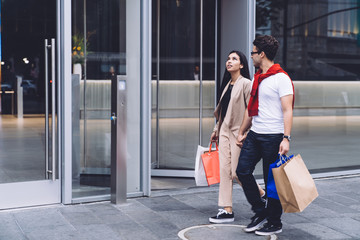 Pleased couple shopping with paper bags in hands