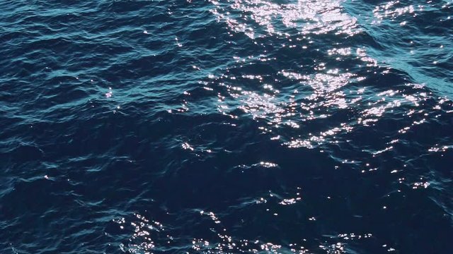 Slow Mo. Beautiful sunlit blue sea waves. Real water ripple on the surface of the sea. Close up liquid textured surface background