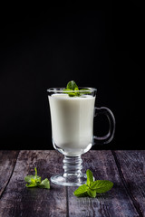 Ayran in a glass, sour-milk drink, yogurt, decorated with a leaf of mint. On a wooden background