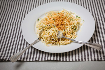 Vegan spaghetti on a white plate; gray and white napkin on gray countertop