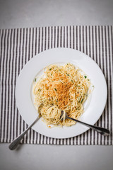 Vegan spaghetti on a white plate; gray and white napkin on gray countertop