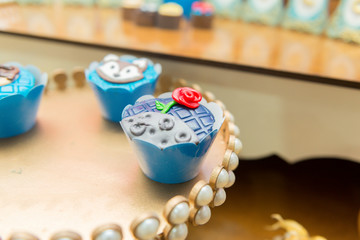 Closeup of decorated chocolate candies in a golden tray decorated by pearls. Kids birthday party decoration. Little prince theme party. Selective focus.