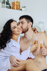 couple sitting in the kitchen, in a white shirt, drinking champagne, christmas