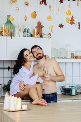 couple in the kitchen with christmas decoration, drink champagne, celebrate new year