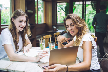 Cheerful woman showing friend information on laptop