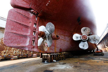 A ship stands in a dry dock in a shipyard. Large propellers of a marine vessel.