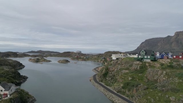 Drone, aerial, rising, wide shot of homes and roads on the edge of cliff next a cove of water.