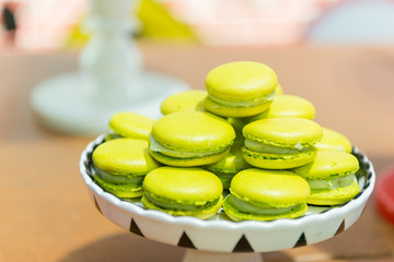 Lemon Macaroons. Several lemon-flavored green macaroons on a white and black ceramic tray. Children's party decoration with the detective theme. Selective focus with blur.