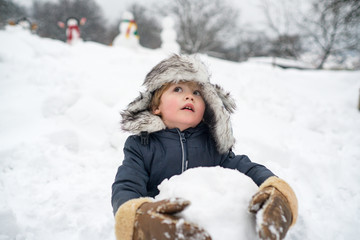 Fototapeta premium Funny boy posing on winter weather. Enjoying nature wintertime. Child playing with Snowman on snow background. People in snow. Snowman.