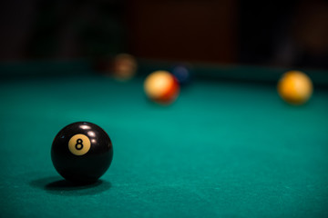 Close -up of billiard 8 ball on billiard table with other balls in the background