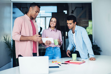 Fototapeta premium Happy colleagues in casual clothing enjoying online browsing and networking on modern digital tablet during work break form brainstorming on info for business project, concept of web technology