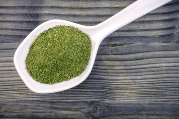 Coarse grind Mitragynina speciosa or Kratom powder in white ceramic spoon