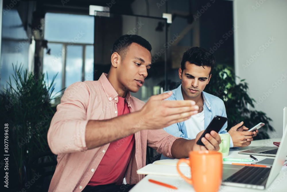 Poster multicultural male colleagues solwing web problems with mobile platform for millennials checking not