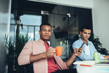 Portrait of millennial employees in casual wear sitting in coworking space near table desktop and posing during time for together brainstorming, diversity executive marketers looking at camera