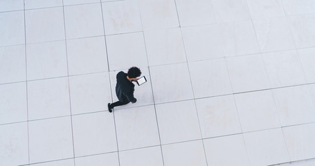 Man walking on white floor and using tablet