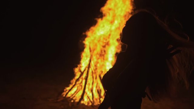 Silhouette of mystic woman in black background of fire fly flame, spark, of contour outline. Adult sexy of young girl witchcraft ceremony ritual dance in underclothes. Outdoor slow motion. Caucasian.