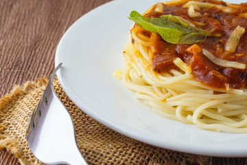 Close up picture of spageeti bolognese with shiny silver fork over brown background