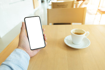 Mockup image blank white screen cell phone.men hand holding texting using mobile on desk at home office. background empty space for advertise text.people contact marketing business and technology 