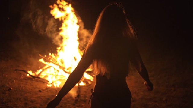 Silhouette of mystic woman in black background of fire fly flame, spark, of contour outline. Adult sexy of young girl witchcraft ceremony ritual dance in underclothes. Outdoor slow motion. Caucasian.