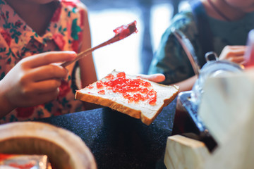 Hand holding bread and Strawberry jam making for breakfast.