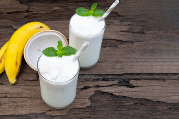 Coconut blend banana milk smoothie drink fresh cocktail shake milkshake vanilla juice fruit beverage food healthy the taste yummy In glass on wooden background.