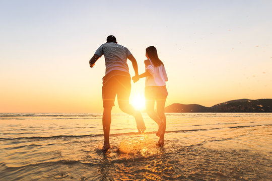 couple running and hand hold on the beach between sunset.