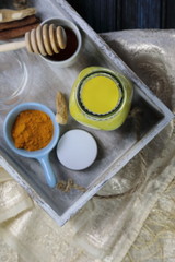 Turmeric latte, golden milk or the anti-inflammatory Indian Haldi Doodh with superfood Turmeric powder, Ginder and Cinnamon sweetened with honey on wooden background