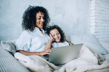 Happy mom and child using laptop on couch at home