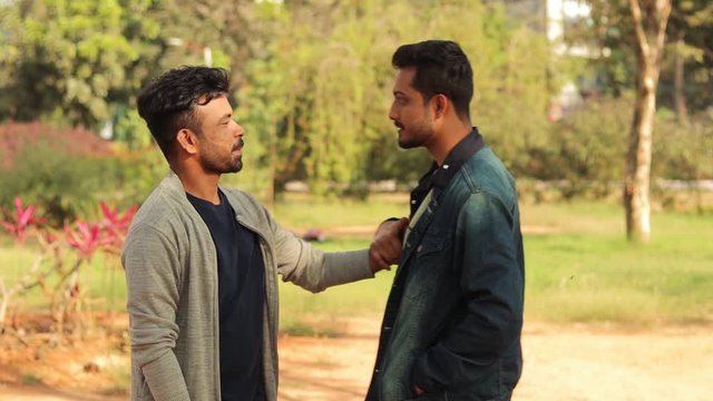 Two male young adults angry and flighting - College student bullies threatening to hit his classmate at university outdoor - Two Asian Youth manhandling each other and arguing.