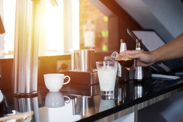 the barista make ice coffee and milk in the cup.