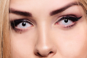 Fototapeta premium White lenses on a blonde. Eye close-up. Gorgeous eye makeup. How to wear a lens, colored lenses. No pupils