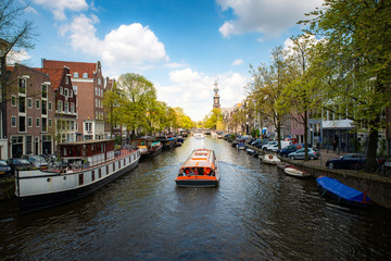 Amsterdam canal with cruise ship with Netherlands traditional house in Amsterdam, Netherlands. Landscape and culture travel, or historical building and sightseeing concept.