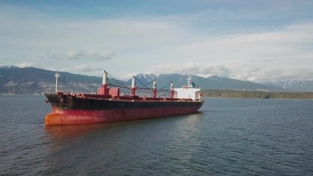 Aerial shot approaching a bulk carrier ship anchored in Burrard inlet near Vancouver, BC, Canada