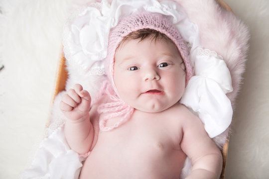 New baby girl smiling in newborn portrait in pink and soft textures