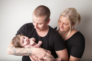 New family, mom and dad holding new baby on white background